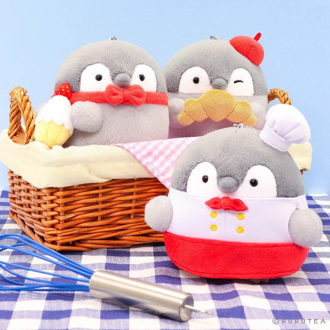 Officially licensed Spiralcute Koupen Chan Bakery Series plush mascot keychain charms featuring the cute grey penguin dressed as a patissier, holding a strawberry cupcake, and eating a croissant, crafted from soft fuzzy textured fabric, perfect for adult kidult collectors as a kawaii aesthetic backpack accessory or office desk decoration.