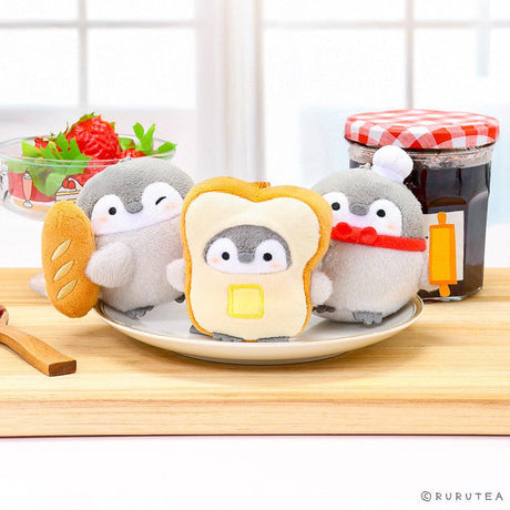 Official Spiralcute Koupen Chan Bakery Series Plush Mascot Keychain Collection featuring a winking penguin holding a baguette, a penguin inside a buttered toast costume, and a chef penguin with a rolling pin, displayed on a white plate and wooden cutting board to serve as a comforting workplace healing companion and emotional support tool for adult kidult collectors.