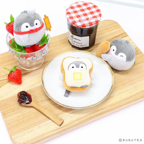 Official Spiralcute Koupen Chan Bakery Series Plush Mascot Keychain Collection featuring a chef penguin with a rolling pin in a strawberry glass bowl, a penguin inside a buttered toast costume on a white plate, and a winking penguin holding a baguette, arranged on a wooden cutting board with a jam jar to serve as a comforting workplace healing companion and emotional support tool for adult kidult collectors.
