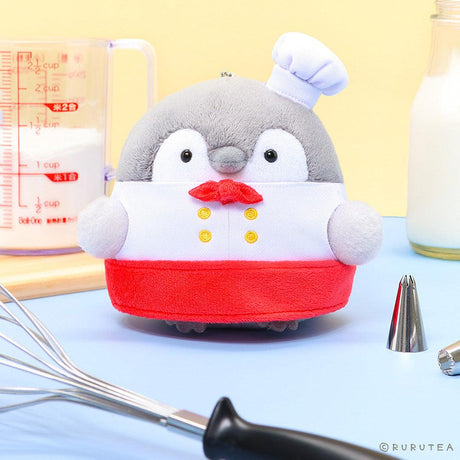 Officially licensed Spiralcute Koupen Chan Bakery Series plush mascot keychain featuring the cute grey penguin wearing a white patissier uniform with yellow buttons, a red bow tie, a red apron, and a tilited white baker hat, with a silver ball chain, made of soft fuzzy material for adult kidult collectors as a kawaii aesthetic bag accessory or collectible plush charm.