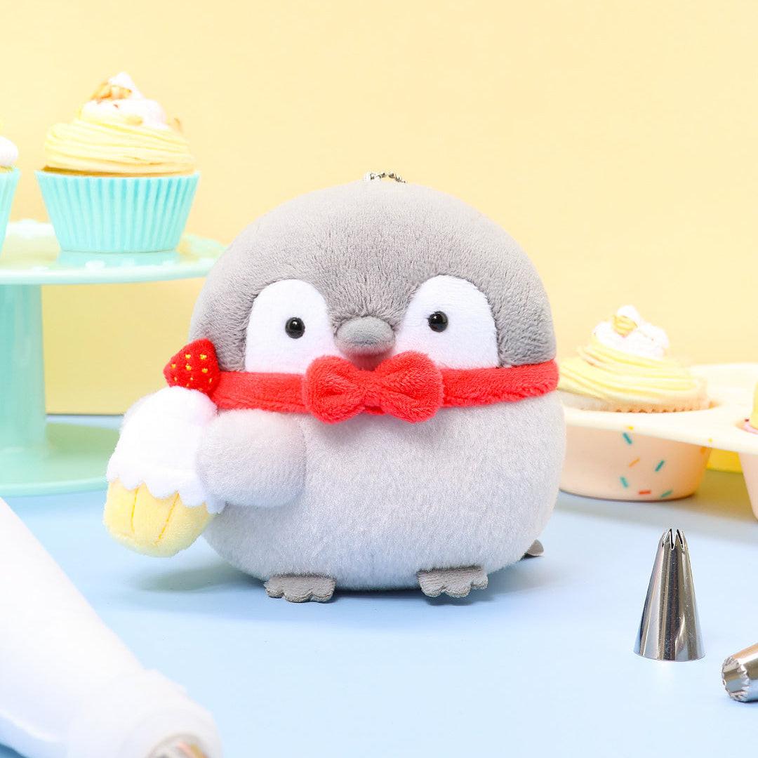 Officially licensed Spiralcute Koupen Chan Bakery Series plush mascot keychain featuring the cute grey penguin wearing a bright red bow tie and holding a miniature strawberry cupcake, with a silver ball chain, made of soft fuzzy material for adult kidult collectors as a kawaii aesthetic bag accessory or collectible plush charm.