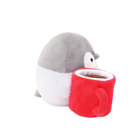 Front view of a grey Koupen Chan penguin plush holding a textured red plush mug with a white flower logo. Dreamy clouds and mint green background. Premium tactile gift idea for fans of Japanese kawaii culture.