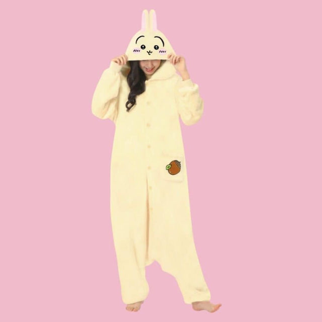 Officially Licensed SAZAC Chiikawa Usagi Kigurumi Onesie worn by a model against a pink background featuring attached rabbit ear hood and acorn pocket patch