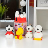 Officially licensed Peanuts Snoopy and Woodstock Squishu water-filled squishy figures in various poses displayed alongside a red surprise capsule