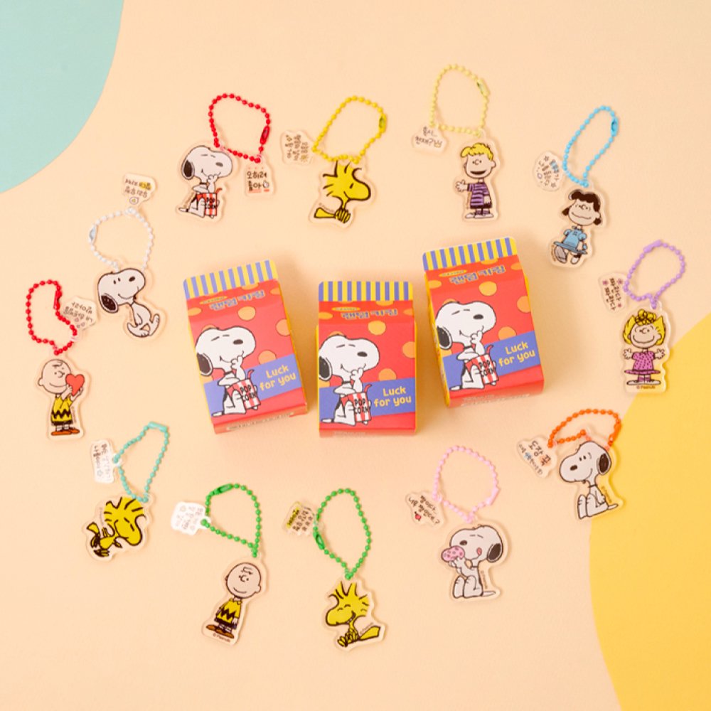 A collection of 12 different Peanuts character acrylic keychains in "Luck For You" blind boxes. The keychains feature Snoopy, Woodstock, Charlie Brown, Lucy, Linus, and Sally.