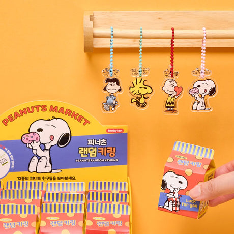 A collection of 12 different Peanuts character acrylic keychains in "Luck For You" blind boxes. The keychains feature Snoopy, Woodstock, Charlie Brown, Lucy.