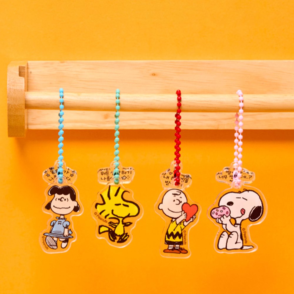 A collection of 12 different Peanuts character acrylic keychains in "Luck For You" blind boxes. The keychains feature Snoopy, Woodstock, Charlie Brown, Lucy.