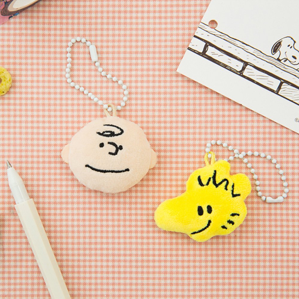 Officially licensed Peanuts plush keychains featuring the faces of Charlie Brown and Woodstock attached to a white ball chain.