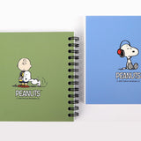An overhead shot showing multiple officially licensed Peanuts spiral notebooks in green and blue layouts, showcasing the different vintage-inspired cover designs and black spiral bindings.