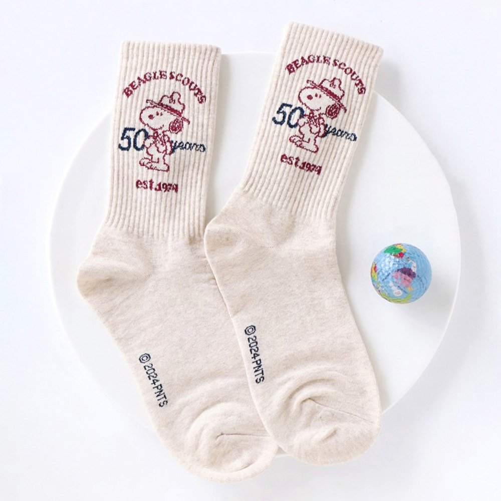 A set of five crew-length socks in black, beige, white, green, and mustard yellow. Each sock features an embroidered graphic of Snoopy as a Beagle Scout leader.