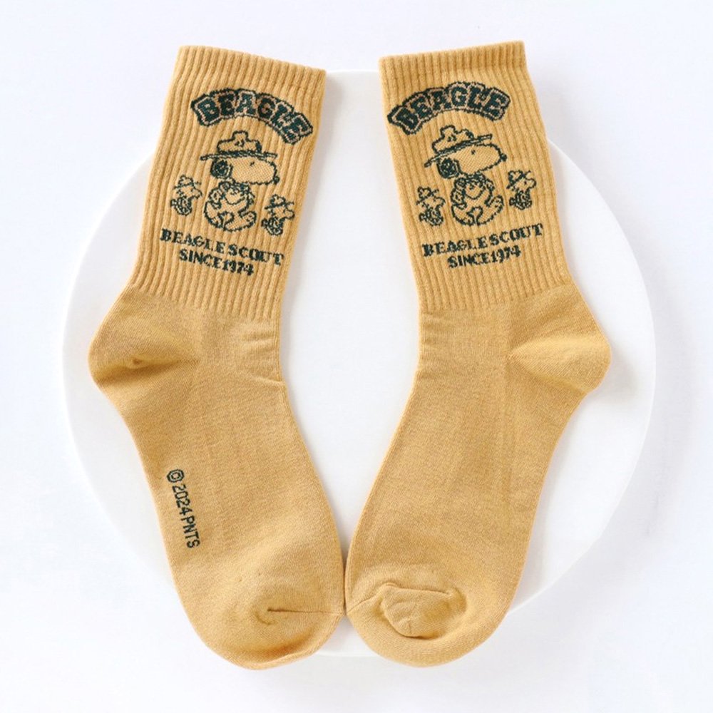 A set of five crew-length socks in black, beige, white, green, and mustard yellow. Each sock features an embroidered graphic of Snoopy as a Beagle Scout leader.