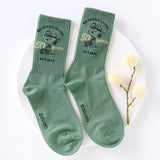 A set of five crew-length socks in black, beige, white, green, and mustard yellow. Each sock features an embroidered graphic of Snoopy as a Beagle Scout leader.