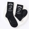 A set of five crew-length socks in black, beige, white, green, and mustard yellow. Each sock features an embroidered graphic of Snoopy as a Beagle Scout leader.