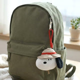 An officially licensed collection of Peanuts Snoopy Camp House mini plush pouches in safari hat, hanging on the backpack.