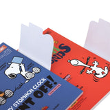 Two officially licensed Peanuts notebooks in red and blue featuring Snoopy and Charlie Brown. The image demonstrates the unique "wing" cover flaps being used as bookmarks and page markers within the lined journal pages.
