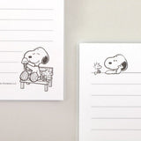 Three officially licensed Peanuts line notebooks with translucent covers in soft hues of pink, yellow, and green, each featuring a large illustration of Snoopy. The interior view shows 8mm ruled pages with small Snoopy graphics at the top and bottom corners.
