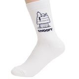 A pair of crew-length socks in white. Features a white embroidered graphic of Snoopy sleeping on top of his doghouse with "SNOOPY" text below.