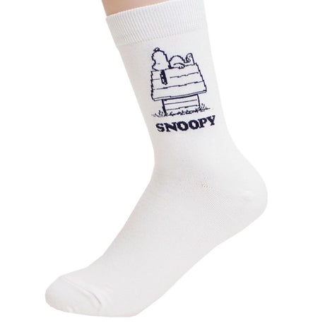 A pair of crew-length socks in white. Features a white embroidered graphic of Snoopy sleeping on top of his doghouse with "SNOOPY" text below.