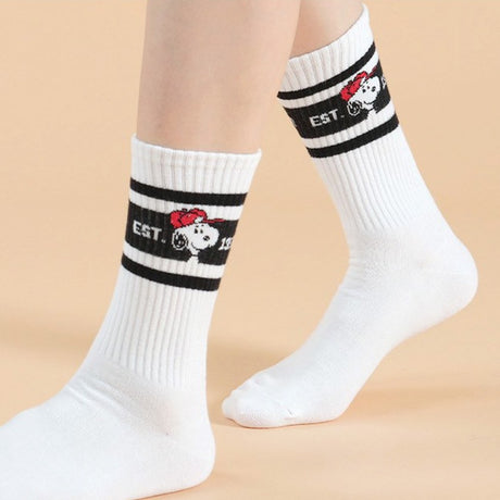 A set of five athletic crew socks in colored stripes of black, pink, green, light blue, and white. Snoopy's face wearing matching colored caps. All socks feature "EST. 1950" text and "SNOOPY" branding on the soles.