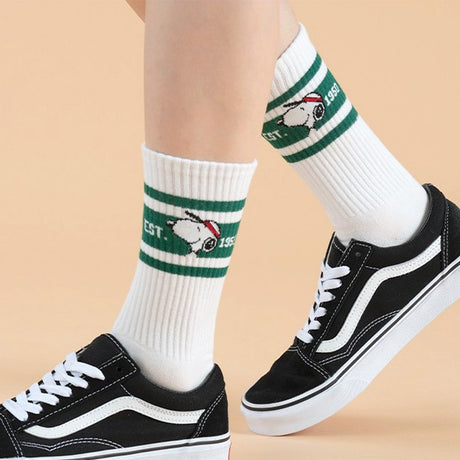 A set of five athletic crew socks in colored stripes of black, pink, green, light blue, and white. Snoopy's face wearing matching colored caps. All socks feature "EST. 1950" text and "SNOOPY" branding on the soles.