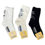 A set of three crew-length socks in white, beige, and black, celebrating Snoopy's 75th anniversary. Features clean, line-art illustrations of Snoopy and Woodstock in their most recognizable poses.