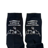 A set of three crew-length socks in white, beige, and black, celebrating Snoopy's 75th anniversary. Features clean, line-art illustrations of Snoopy and Woodstock in their most recognizable poses.
