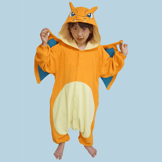 Official Pokémon Charizard Kids Costume Kigurumi Onesie Jumpsuit worn by a young model spreading the attached dragon wings. Features a bright orange fleece body, cream belly panel, and a Charizard face hood with horns. Perfect for kids' Halloween costumes, sleepover parties, and year-end holiday gifts.