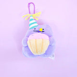 A Pokémon Ditto plush keychain holding a celebration cupcake and wearing a striped party hat with yellow yarn on top, attached to a colorful ball chain