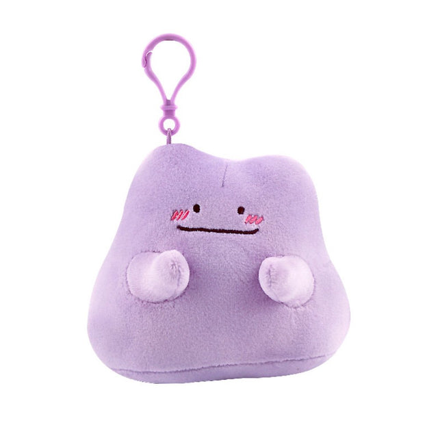 An officially licensed Pokémon Ditto plush clip-on keychain in a vibrant light purple color. The plush features a simple smile, and three pink diagonal lines on each cheek to represent blushing.