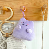 An officially licensed Pokémon Ditto plush clip-on keychain in a vibrant light purple color. The plush features a simple smile, and three pink diagonal lines on each cheek to represent blushing.