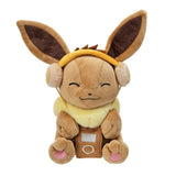 An officially licensed Pokemon Eevee plush toy wearing tan headphones and holding a brown plush music player, featuring a happy, closed-eye expression