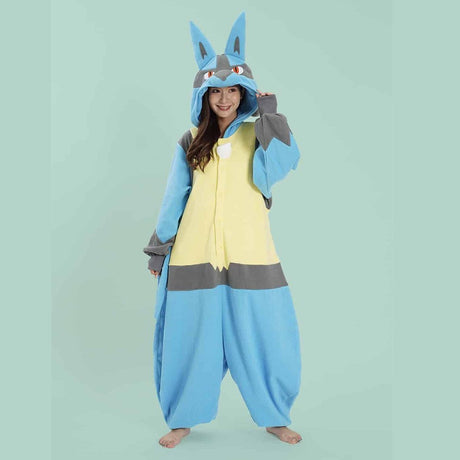 Official Pokémon Lucario Costume Kigurumi Onesie Jumpsuit worn by a smiling model holding the hooded ears. Features a soft blue, grey, and cream-yellow fleece body with a white chest spike detail and red character eyes. A cool cosplay outfit for Halloween costumes, cozy sleepover nights, and year-end holiday party loungewear for adult Pokémon fans