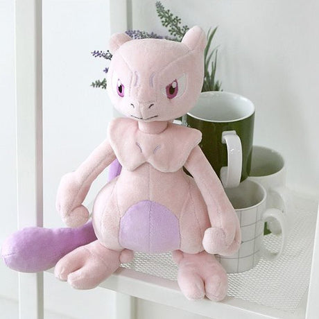A soft plush toy of the Pokémon Mewtwo, featuring its light purple body, darker purple belly, and long tail, standing upright on a white background