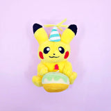 A Pokémon Pikachu plush keychain holding a celebration cupcake and wearing a striped party hat with yellow yarn on top, attached to a colorful ball chain