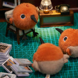 A round, fluffy Asian Dowitcher bird plush keychain with bright orange and tan fur, a black beak, and small black feet