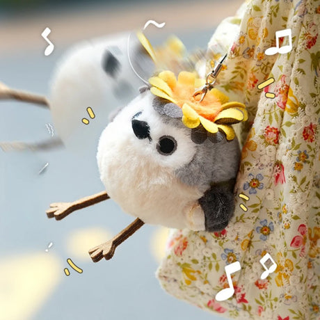 A round, fluffy Goldcrest bird plush keychain with a grey head, cream-colored body, and dark grey wings, wearing a bright yellow head crest, featuring small black eyes and long brown legs