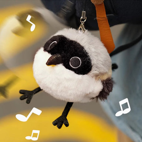 A round, fluffy Long-tailed Shrike bird plush keychain with white and grey fur, a distinct black face mask, and long black legs