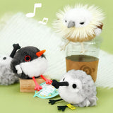 A round, fluffy white and grey Sandpiper bird plush keychain with a black spoon-shaped beak and small black feet