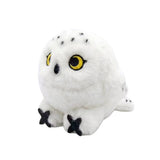 An adorable, round snowy owl plush keychain with fluffy white fur and black speckles on its head and tail. The plush features large, bright yellow embroidered eyes, a tiny black beak, and prominent black talons peeking out from its spherical body.