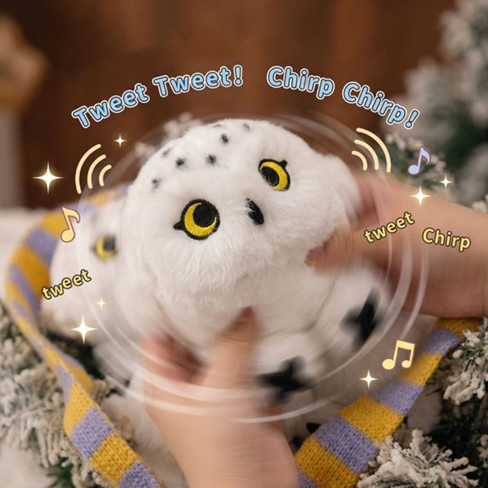 An adorable, round snowy owl plush keychain with fluffy white fur and black speckles on its head and tail. The plush features large, bright yellow embroidered eyes, a tiny black beak, and prominent black talons peeking out from its spherical body.