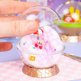A collection of six different officially licensed Kirby terrarium figures. The miniatures feature Kirby in various settings like a snowy landscape, a tropical island, and napping on a tree stump, all enclosed in clear jars or globes.