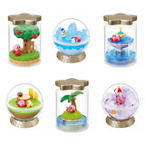 A collection of six different officially licensed Kirby terrarium figures. The miniatures feature Kirby in various settings like a snowy landscape, a tropical island, and napping on a tree stump, all enclosed in clear jars or globes.