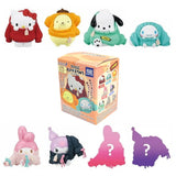 Officially licensed Sanrio Characters Okigaechu Figure Blind Box showing Sanrio characters bundled up in oversized knit sweaters surrounding a mystery box packaging with secret silhouettes