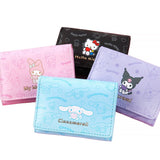 An officially licensed collection of four Sanrio character mini wallets in black, pink, purple, and blue featuring Hello Kitty, My Melody, Cinnamoroll, and Kuromi with gold-lettered names.