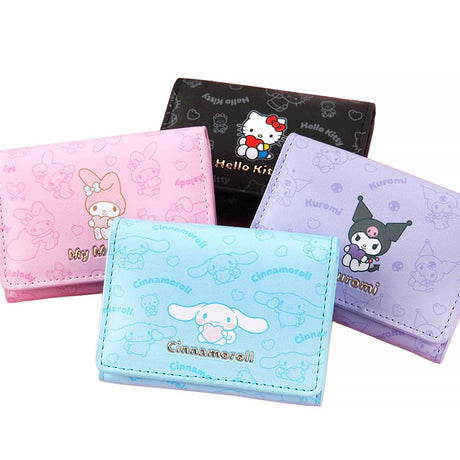 An officially licensed collection of four Sanrio character mini wallets in black, pink, purple, and blue featuring Hello Kitty, My Melody, Cinnamoroll, and Kuromi with gold-lettered names.