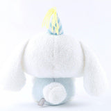 Officially licensed Sanrio Cinnamoroll plush, wearing a charming white party hat topped with a bright yellow tassel, and holding a cake for celebrating a special day.