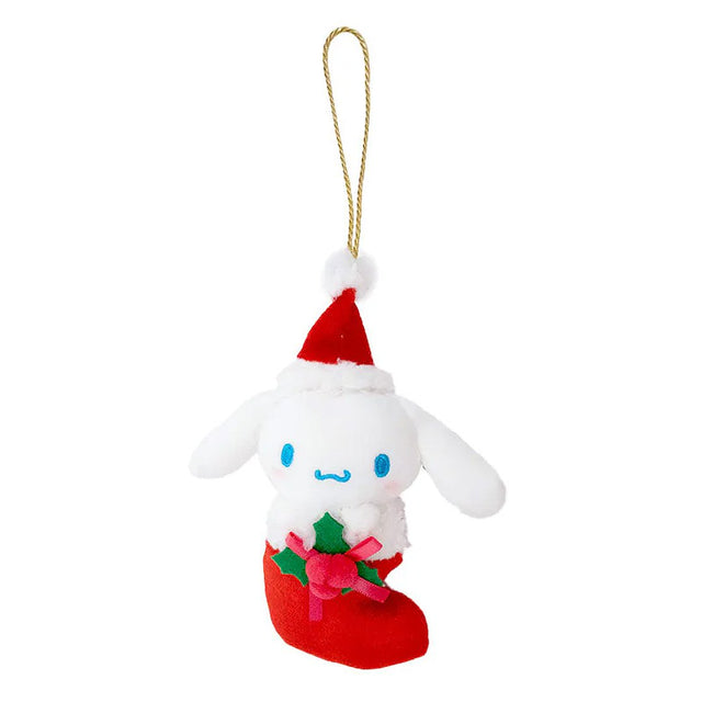 Sanrio Cinnamoroll is dressed for the season wearing a red Santa hat with a white pom-pom while sporting his signature red bow. He sits snugly in a red Christmas stocking adorned with green holly leaves and a decorative ribbon. Crafted from soft plush material, this ornament has a cozy, huggable feel. The attached gold cord loop makes it easy to hang on your Christmas tree.