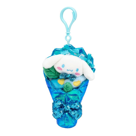 An officially licensed Sanrio Cinnamoroll plush bouquet keychain featuring a white plush character and blue flowers wrapped in shimmering iridescent blue fabric. The bouquet is decorated with blue satin bows and a large, sparkling blue sequined bow at the bottom.