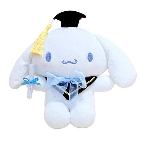An officially licensed Sanrio 10-inch Cinnamoroll graduation plush sitting upright, wearing a black graduation cap with a yellow tassel and a blue bow around the neck while holding a white diploma
