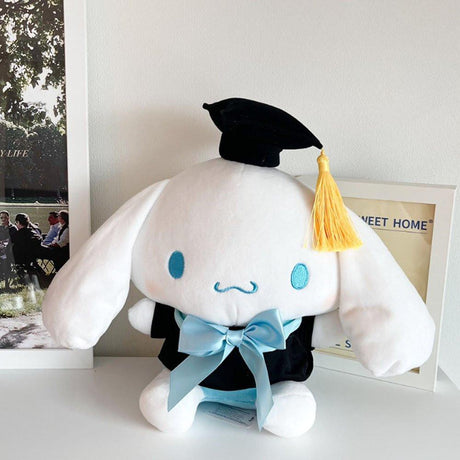 An officially licensed Sanrio Cinnamoroll plush toy dressed in a black graduation cap with a gold tassel and a matching gown featuring a large light blue bow
